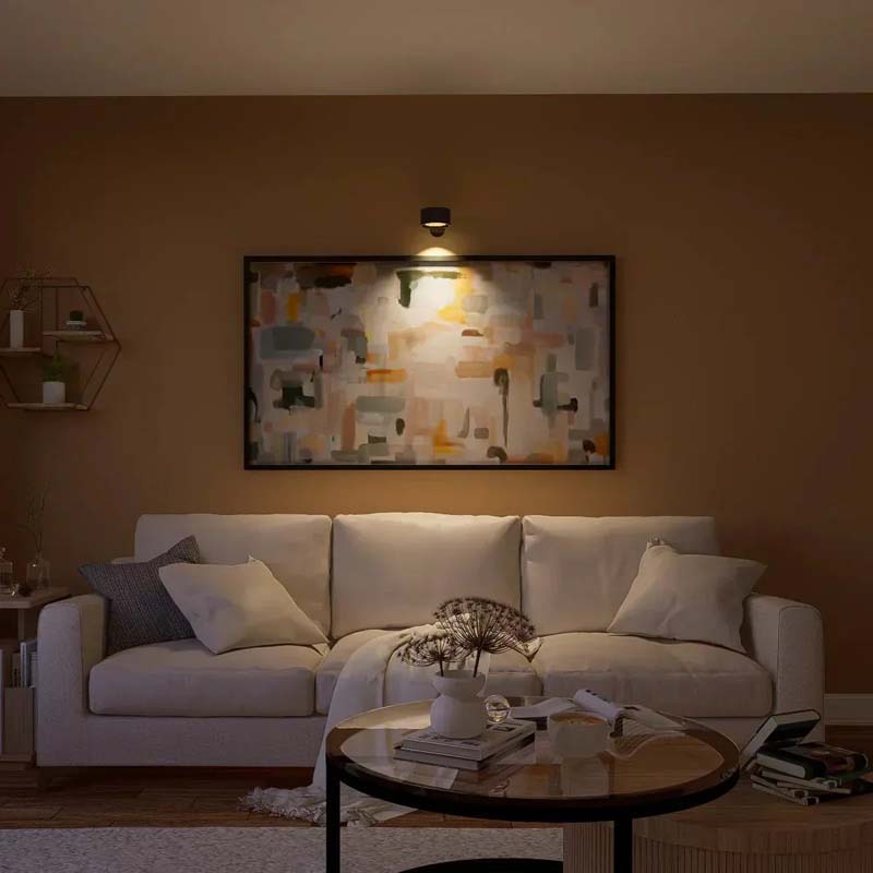 Touch LED Wall Sconce in the living room above a white sofa, coffee table and pictures on the walls.