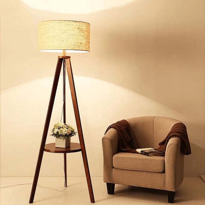 Triangular wooden floor lamp with a beige lampshade next to a beige armchair in a softly lit room.