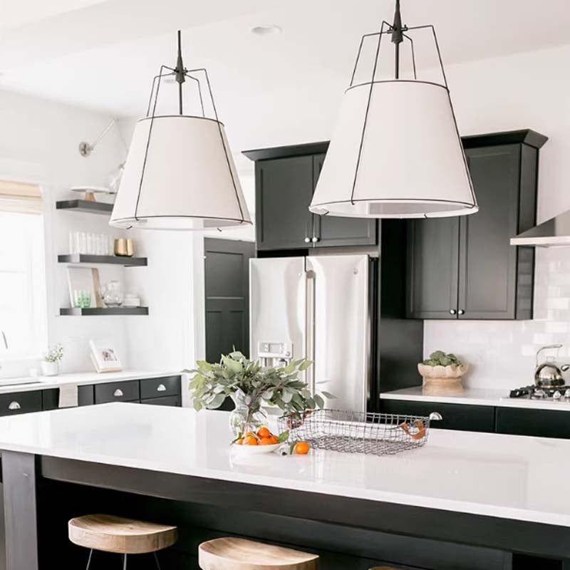 Two white Pendant Lampshade Comfort lamps in a contemporary kitchen with black cabinets and white countertops.
