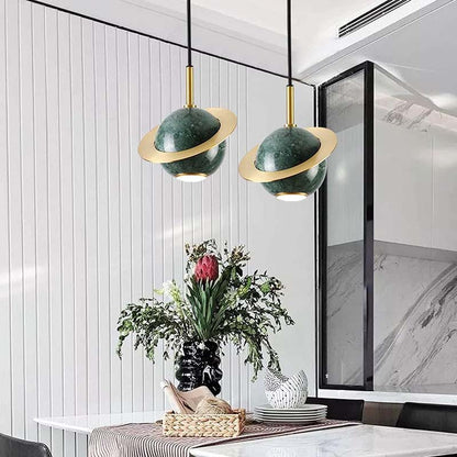 Modern interior design with green and gold pendant lights, a vase of flowers, and a marble countertop.
