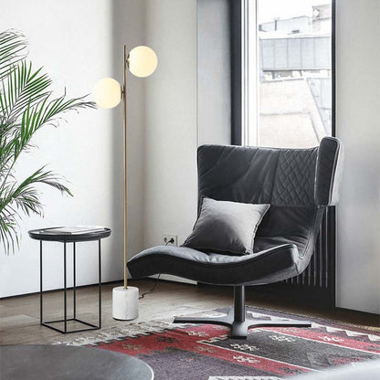 Two Spheres floor lamp in a modern living room between a gray armchair and a side table.
