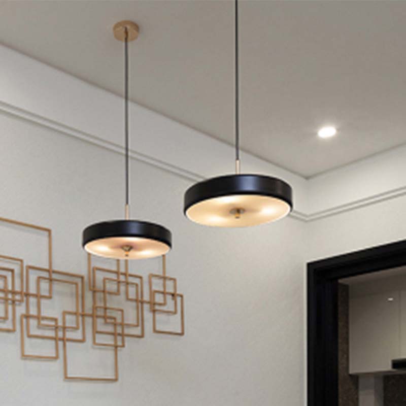 Two modern pendant lights hanging from the ceiling in a room with decorative wall art.