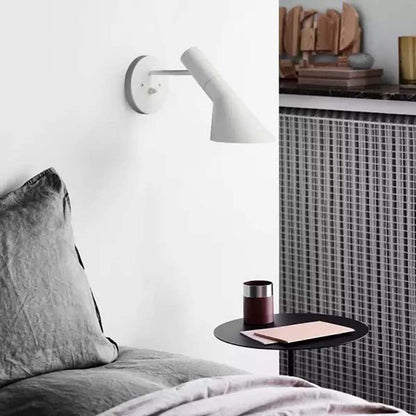 Modern bedroom with a bed, side table, and wall lamp.