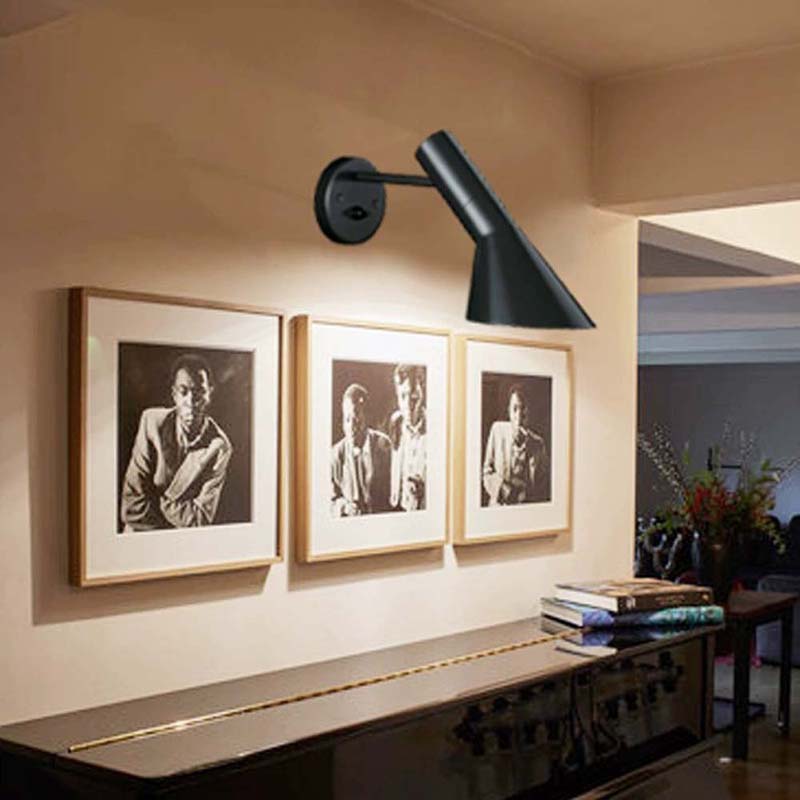 Modern wall lamp above a console table with framed pictures on a wall.