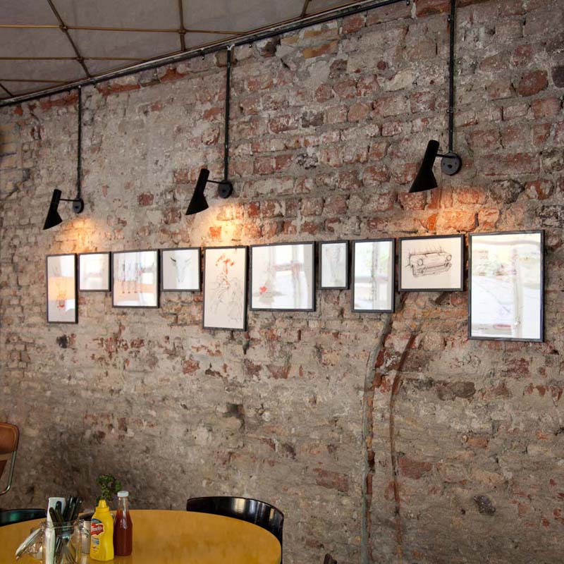 Artistic wall lights on a brick wall with framed pictures below