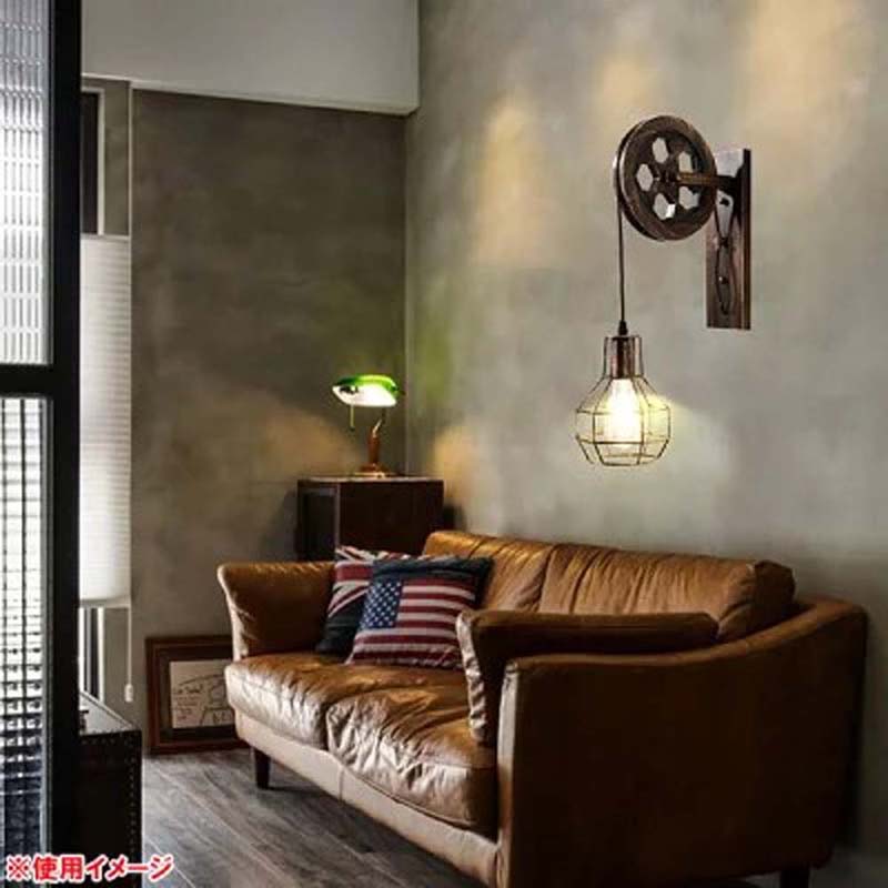 Brown leather sofa with decorative pillows in a room with a wall-mounted industrial-style light fixture.