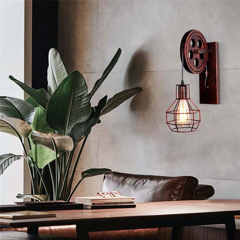 Indoor plant on a table with a wall-mounted industrial-style light fixture in a room.