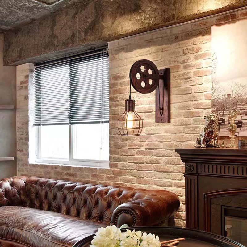 Vintage-style wall lamp on a brick wall with a brown leather sofa and window in the background.