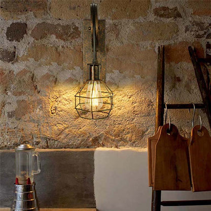 Wall-mounted industrial-style light fixture on a stone wall with a ladder and metal container in the foreground.