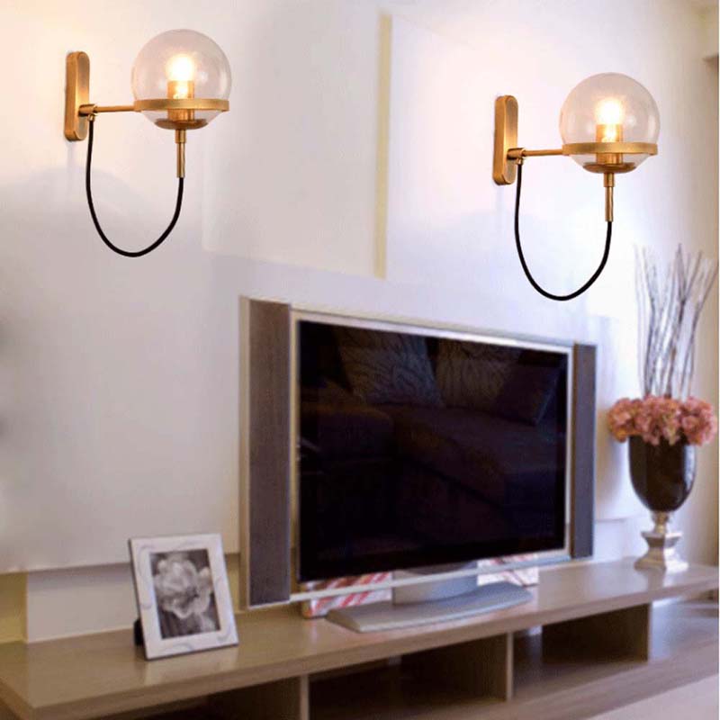 Modern living room with a television on a wooden stand, wall sconces, and decorative items.