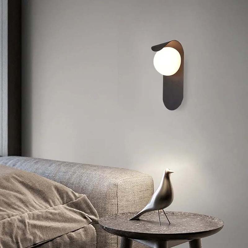 Modern wall lamp on a gray wall with a sofa and decorative bird sculpture in the foreground.