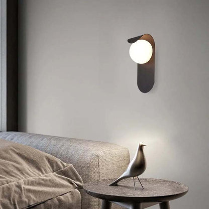 Modern wall lamp on a gray wall with a sofa and decorative bird sculpture in the foreground.