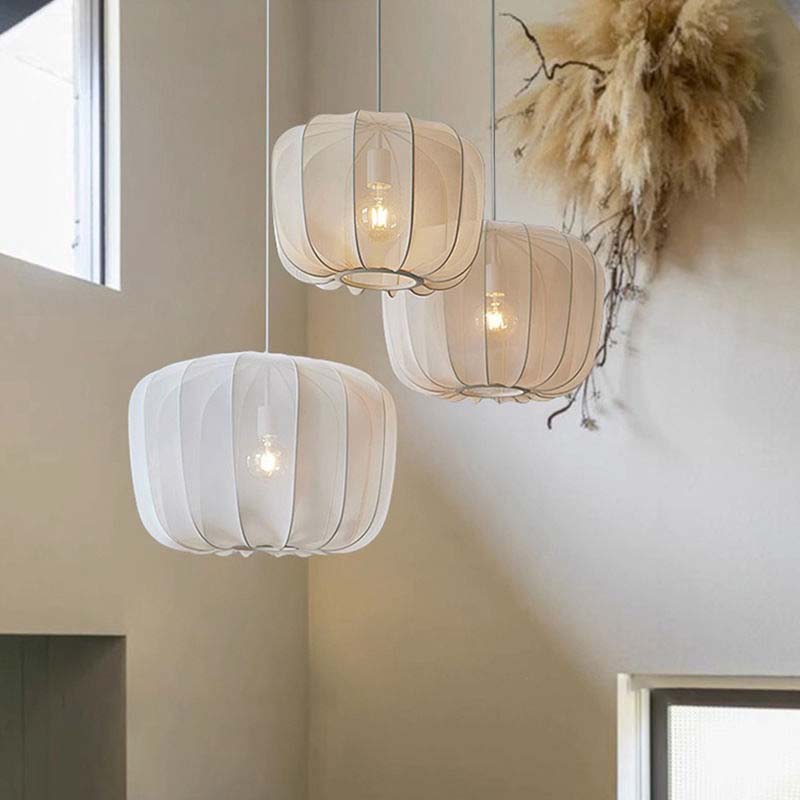 Three hanging pendant lights with white and beige shades in a room setting.