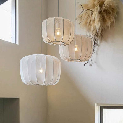 Three hanging pendant lights with white and beige shades in a room setting.