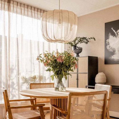 Lantern Pendant Light in a dining room with a wooden table and chairs, flower arrangement and large window.