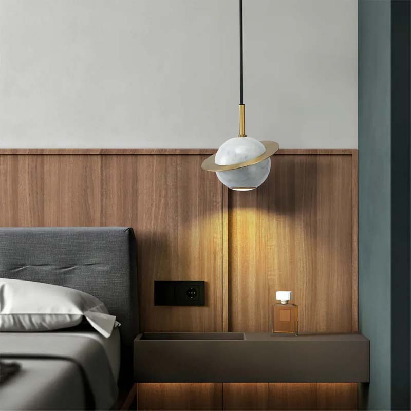 Modern pendant light fixture in a bedroom setting with wooden headboard and bed.