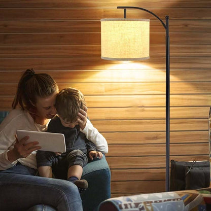 Woman and child sitting together under a floor lamp in a cozy room.