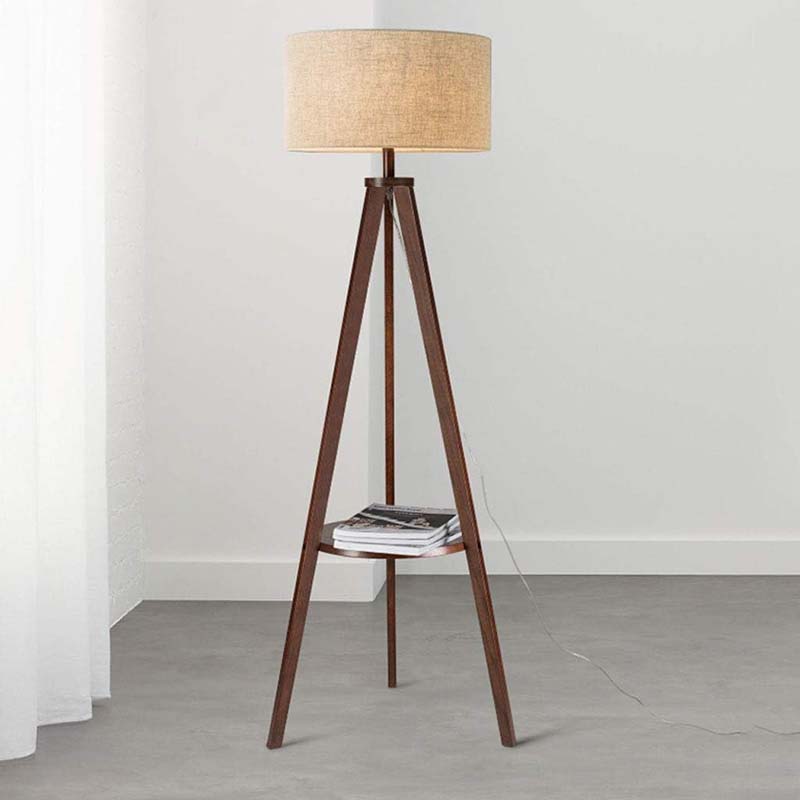 Wooden tripod floor lamp with a beige lampshade on a plain background