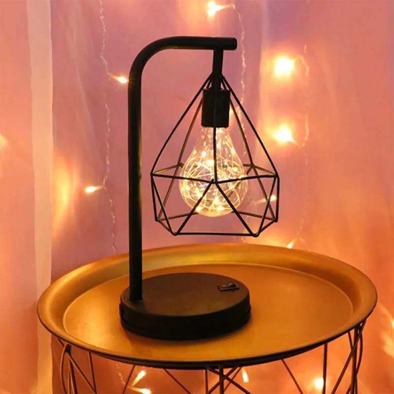 Black Geometric Loft LED Table Lamp on a small table against a backdrop of garland lights