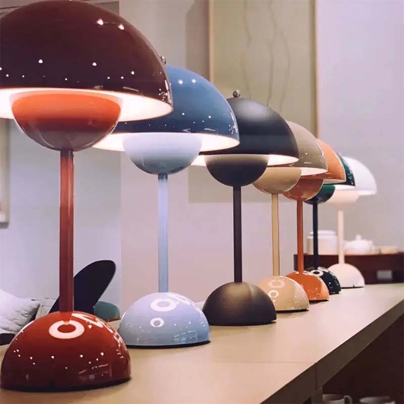 Row of colorful table lamps on a wooden surface with a blurred indoor background