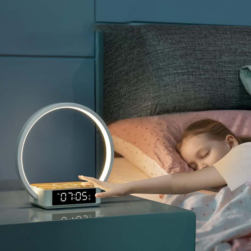 Smart night light with digital clock on a bedside table next to a sleeping child in bed.