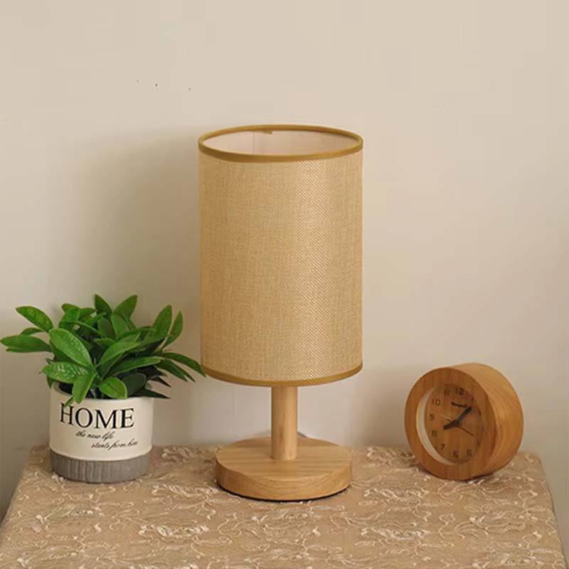 Wood Table Lamp with Natural Fabric Shade on a table between a flower and a clock