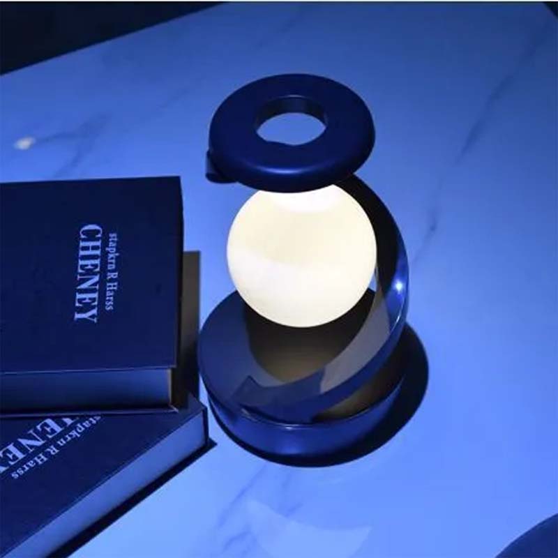 The Saturn Helix – LED Desk Lamp with Wireless Charging is shown next to its signature dark blue box on a blue-lit surface.