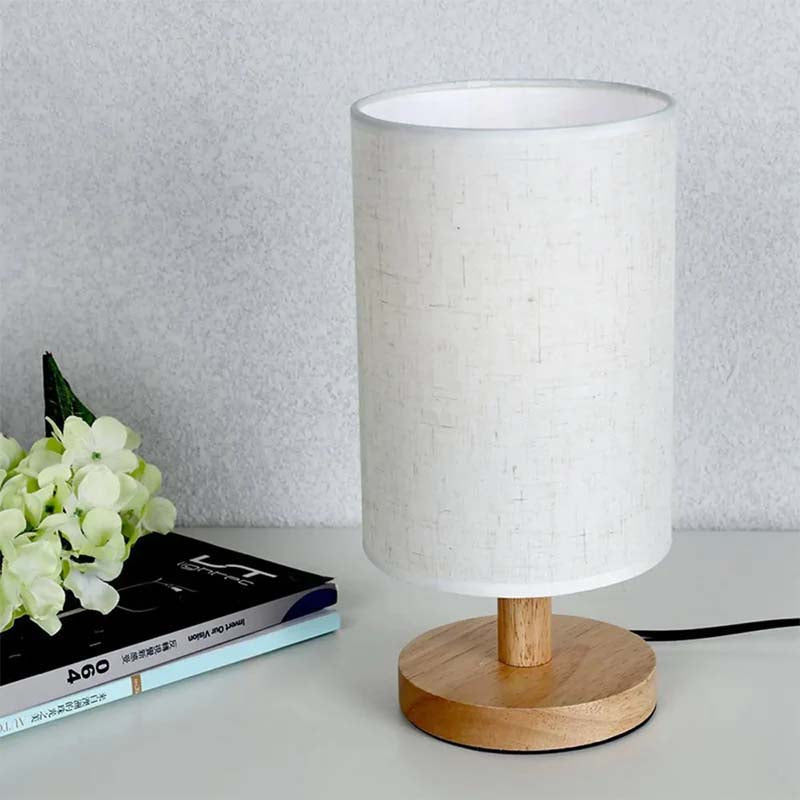Wood Table Lamp with Natural Fabric Shade on a table next to books