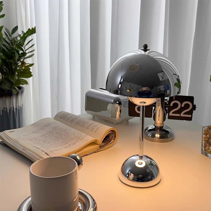 Desk setup with a lamp, book, and cup under soft lighting