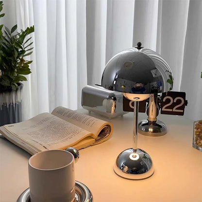 Desk setup with a lamp, book, and cup under soft lighting