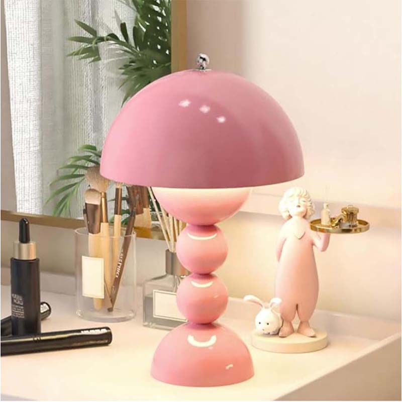 Pink table lamp on a desk with makeup items and decor