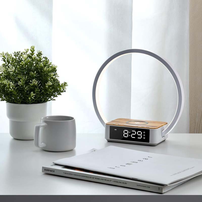 Modern alarm clock with circular design on a desk with a plant and mug