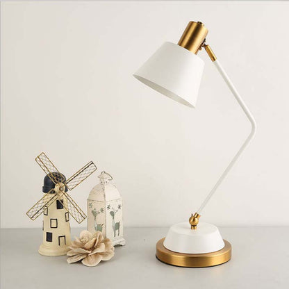 The Modern Adjustable LED Reading Desk Lamp sits on a light gray surface next to decorative miniature figurines.