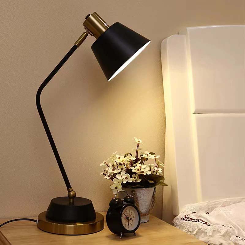 The Modern Adjustable LED Reading Desk Lamp sits on a wooden nightstand next to a small black alarm clock and a vase of flowers.