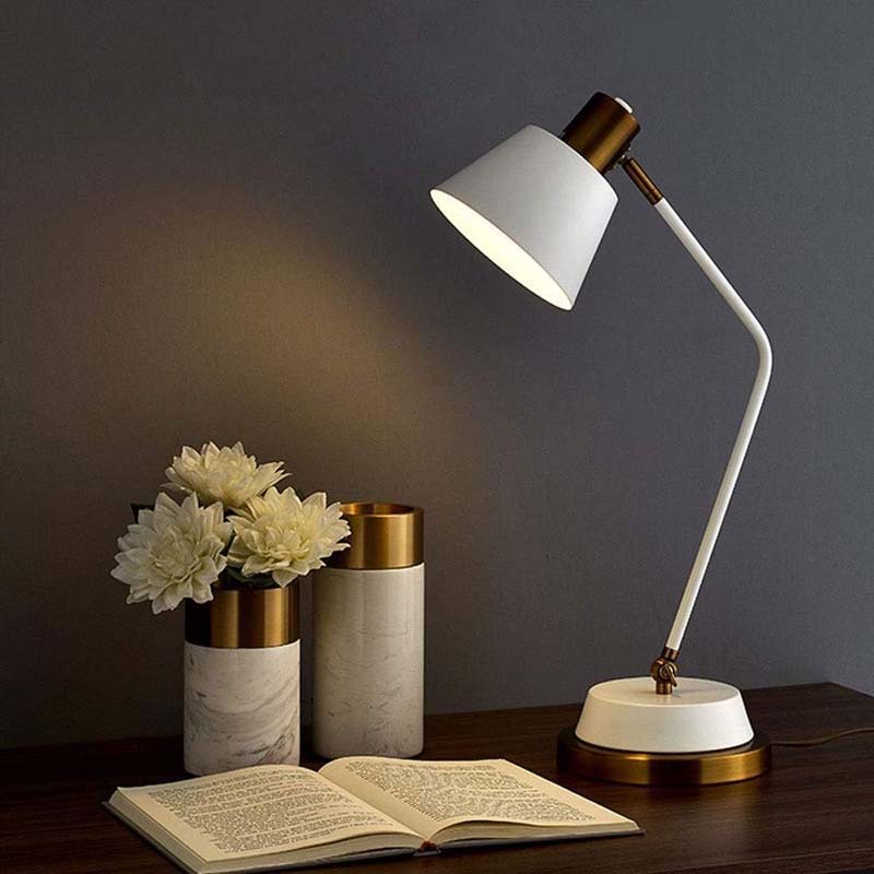 The Modern Adjustable LED Reading Desk Lamp is displayed lit on a dark wooden table next to a book and two marble vases of flowers.