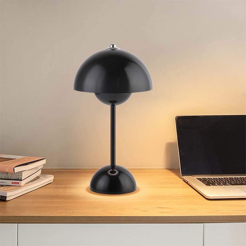 Black table lamp on a wooden desk with a laptop and books