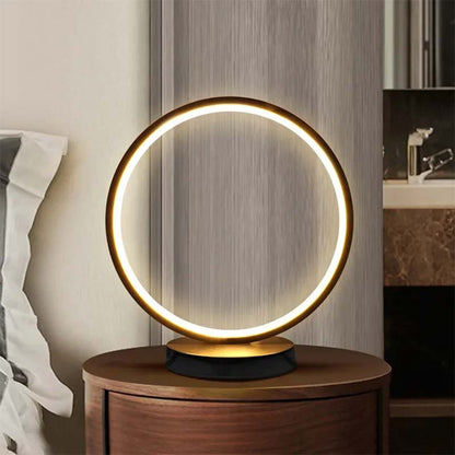 Contemporary LED ring table lamp on nightstand, warm ambient lighting, modern bedroom decor, minimalist home lighting