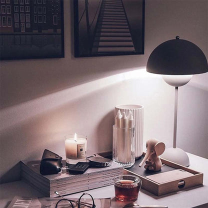 Cozy evening setting with a lit candle, glass of tea, and decorative items on a table.