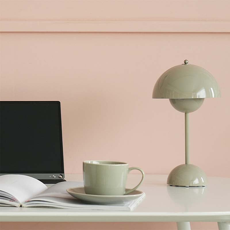 Green lamp and mug on a desk with a pink wall background