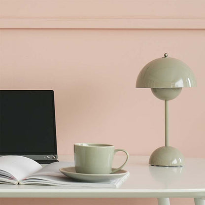 Green lamp and mug on a desk with a pink wall background