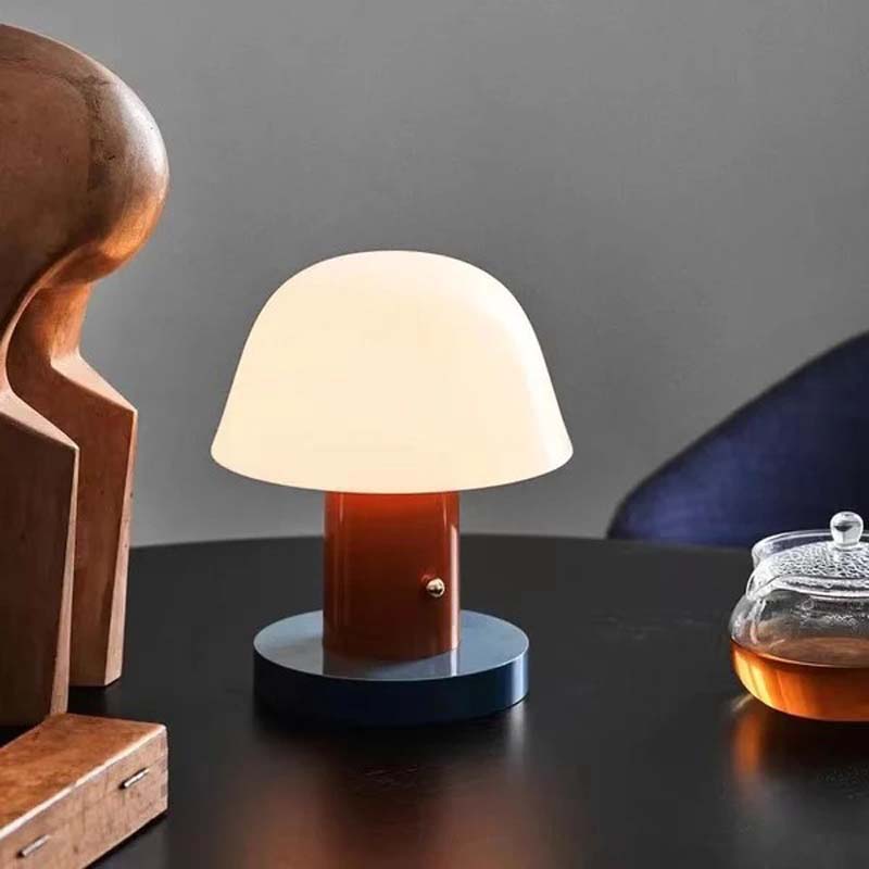 Nordic Mushroom LED Table Lamp with a warm glow, aimed at books, against a blurred background.