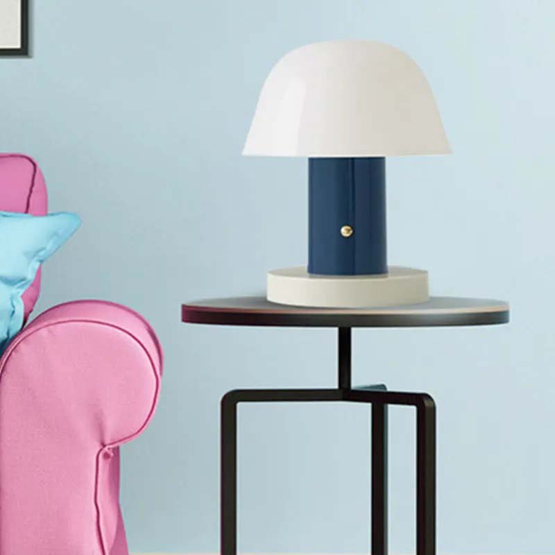 The Nordic Mushroom LED Table Lamp sits on a dark metal side table against a light blue wall.