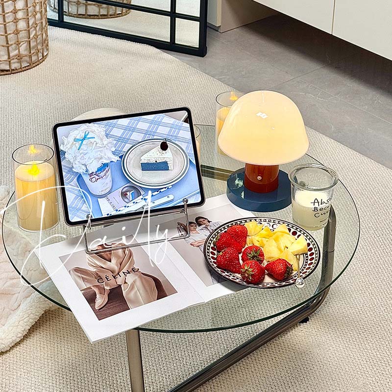 Nordic Mushroom LED Table Lamp stands on a glass coffee table with a tablet on a stand, with candles, a plate of strawberries and fruits