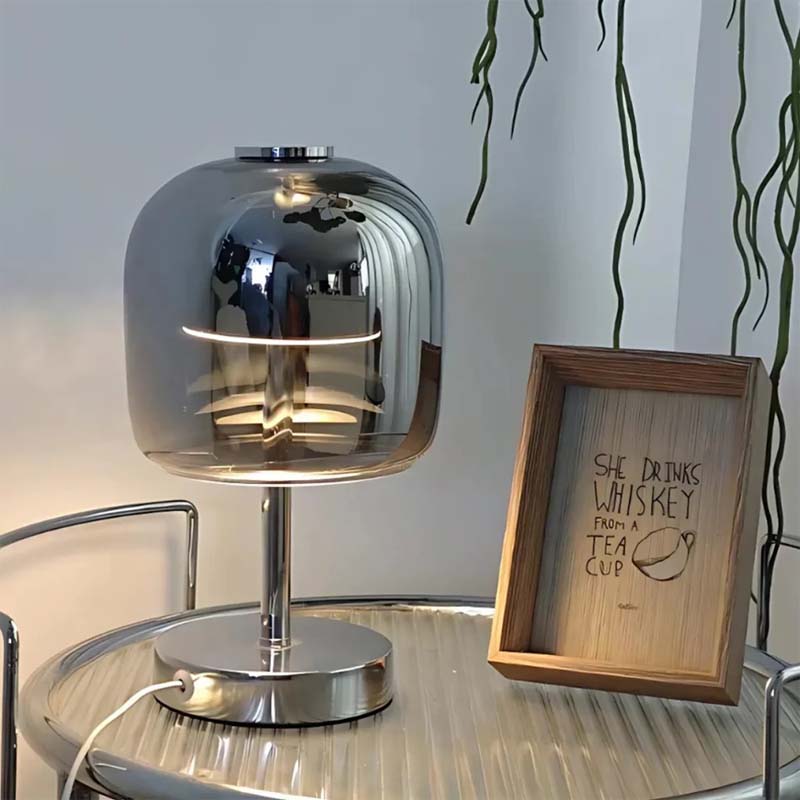 Modern silver table lamp on a glass table with a wooden frame and text.