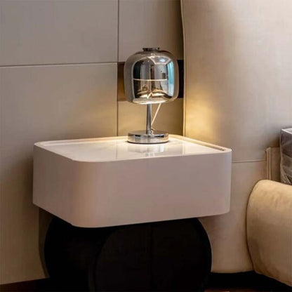 A Premium Glass LED Table Lamp sits on a bedroom nightstand next to a beige upholstered chair.