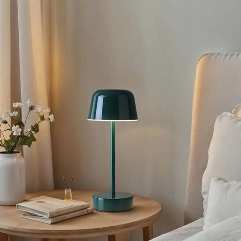 The Rechargeable Cordless Touch LED Table Lamp sits on a light wooden nightstand, emitting a warm glow.