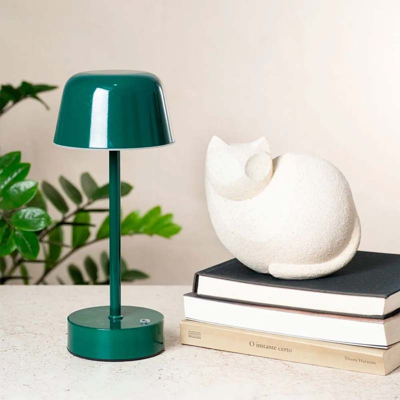 A dark green Rechargeable Cordless Touch LED Table Lamp sits on a light surface next to a white ceramic cat figurine.