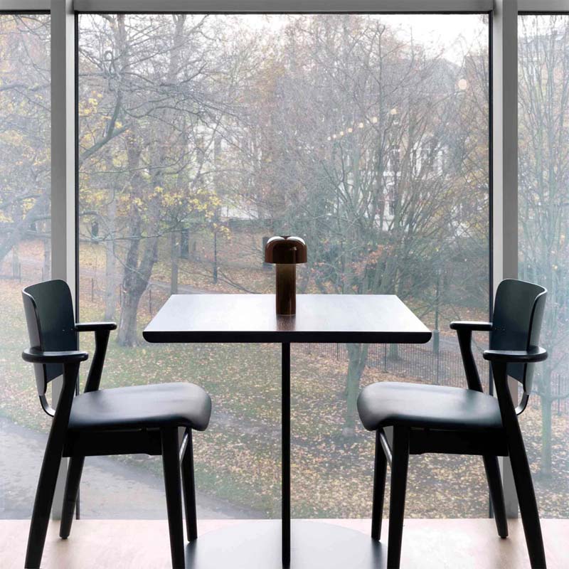 Rechargeable Mushroom LED Table Lamp on a modern black dining table with chairs in a room with large windows
