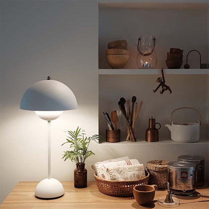 Table lamp on a wooden surface with shelves in the background containing various kitchen items.