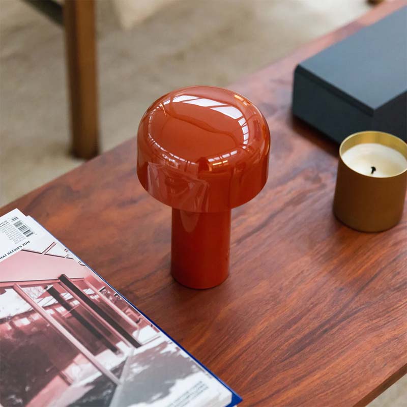Rechargeable Mushroom LED Table Lamp on a wooden surface, next to a magazine and a candle.